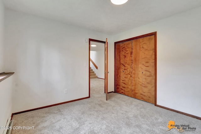 unfurnished bedroom featuring carpet, baseboards, and a closet