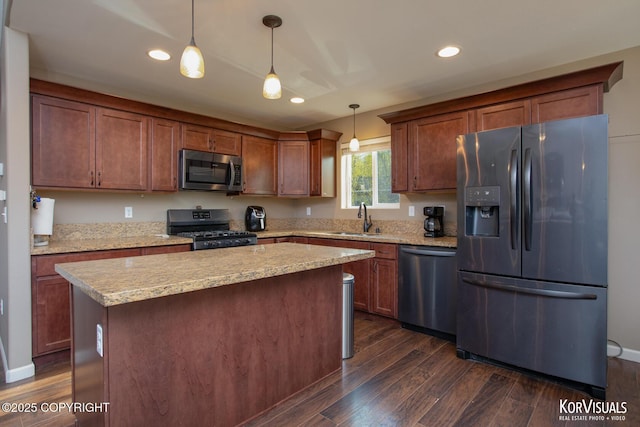kitchen featuring appliances with stainless steel finishes, dark wood-type flooring, a sink, hanging light fixtures, and recessed lighting