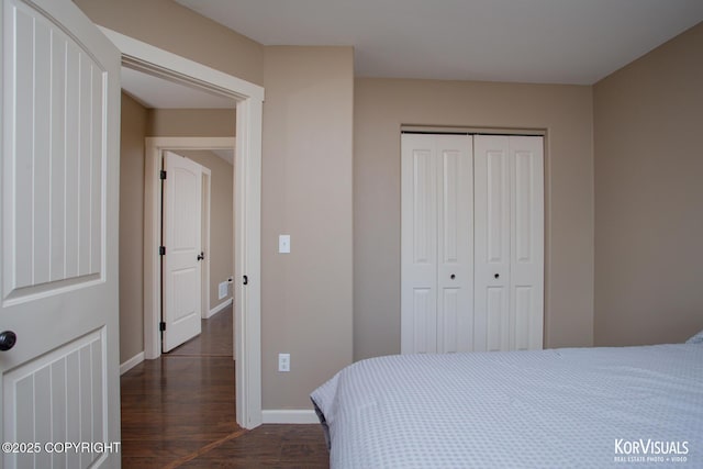 bedroom featuring dark wood-style floors, a closet, and baseboards