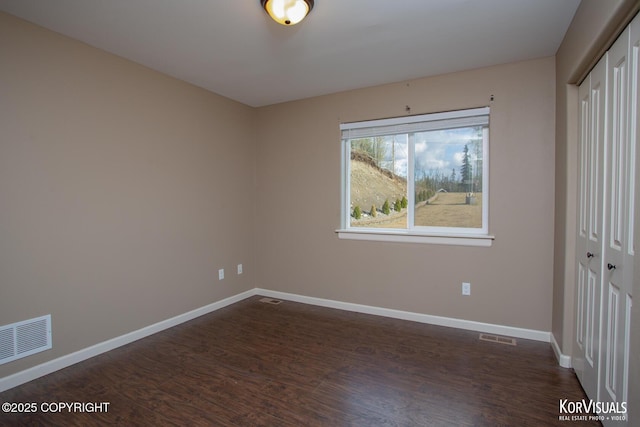 unfurnished bedroom with a closet, dark wood-style flooring, and baseboards