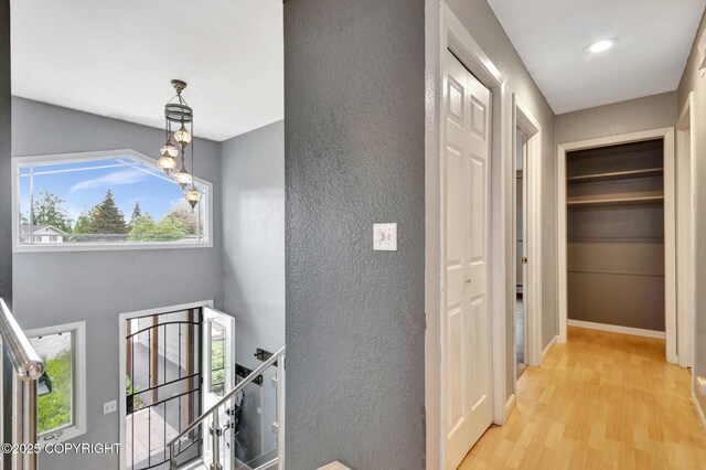 7810 Mae Rene Cir, Anchorage, AK 99502 - hallway with an upstairs landing, light wood-style floors, a textured wall, and baseboards