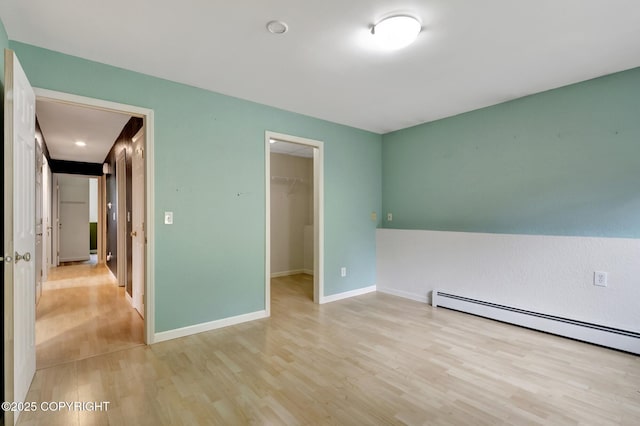 7810 Mae Rene Cir, Anchorage, AK 99502 - unfurnished bedroom featuring light wood finished floors, a walk in closet, a baseboard heating unit, baseboards, and a closet