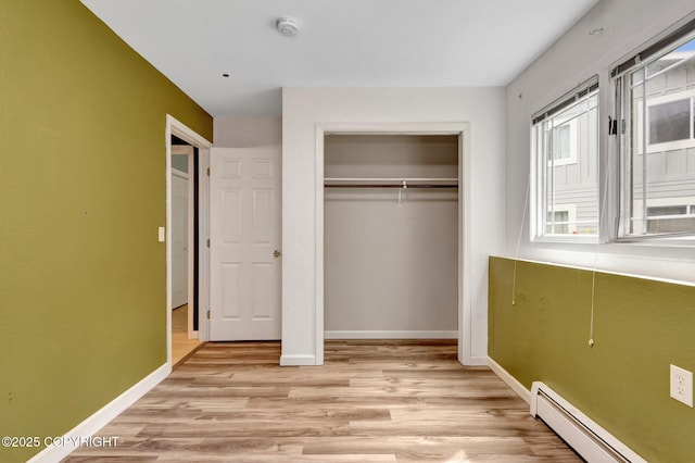 7810 Mae Rene Cir, Anchorage, AK 99502 - unfurnished bedroom featuring a baseboard radiator, light wood finished floors, a closet, and baseboards