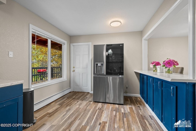 1507 W 47th Ave, Anchorage, AK 99503 - kitchen with blue cabinetry, stainless steel fridge, a baseboard radiator, light wood-style flooring, and a textured wall
