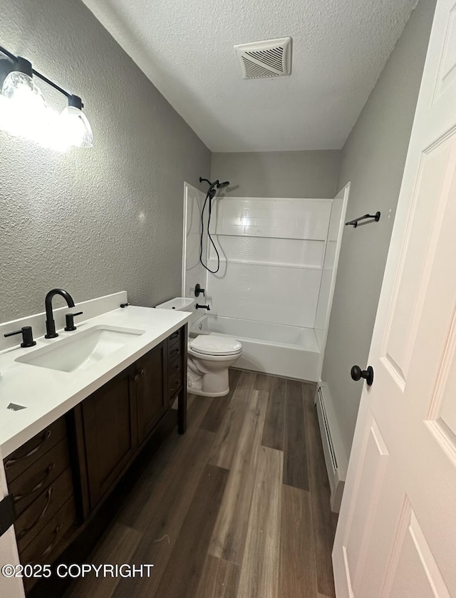 1507 W 47th Ave, Anchorage, AK 99503 - bathroom with baseboard heating, vanity, a textured ceiling, wood finished floors, and bathtub / shower combination