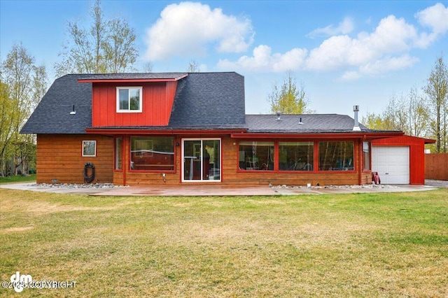 rear view of property featuring an attached garage, a lawn, and a shingled roof