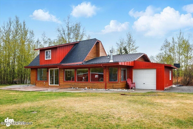 rear view of house featuring a garage, a lawn, and a shingled roof