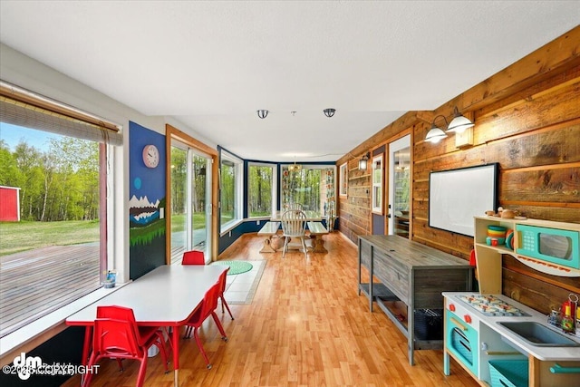 sunroom with healthy amount of natural light, wood walls, and wood finished floors