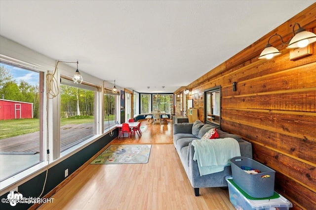 sunroom with plenty of natural light, an outdoor living space, wood finished floors, wooden walls, and a wooden deck