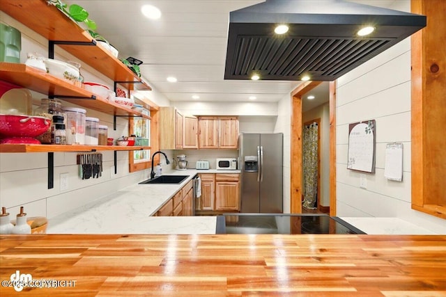 kitchen featuring stainless steel fridge, white microwave, open shelves, custom range hood, and a sink