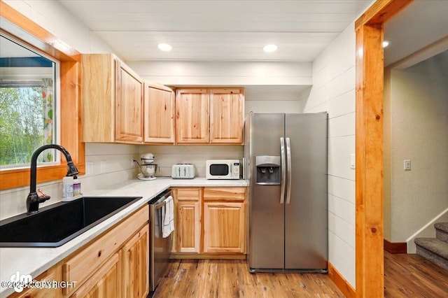 kitchen with appliances with stainless steel finishes, a sink, light wood finished floors, light countertops, and recessed lighting