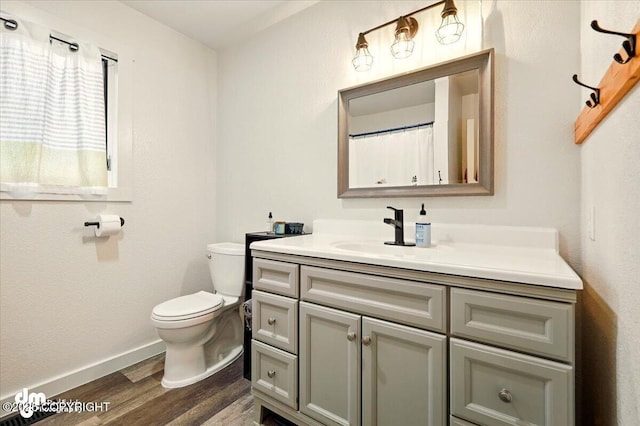 bathroom with wood finished floors, toilet, vanity, and baseboards