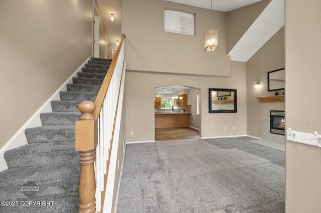16422 Ondola Cir, Eagle River, AK 99577 - stairs featuring a high ceiling, carpet floors, a tiled fireplace, and arched walkways