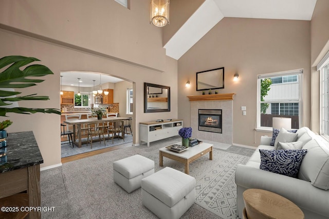 16422 Ondola Cir, Eagle River, AK 99577 - carpeted living room featuring a chandelier, arched walkways, a towering ceiling, and a tiled fireplace