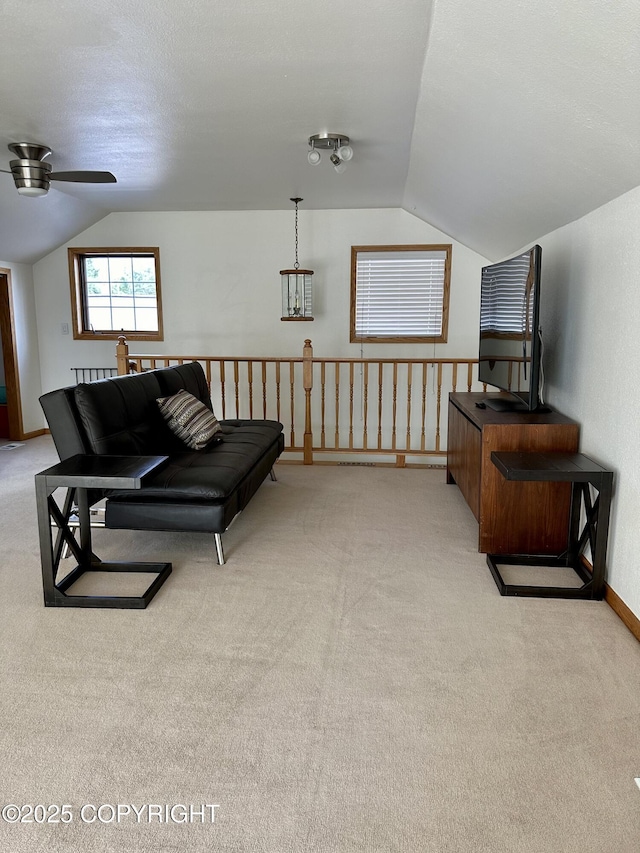 living area featuring vaulted ceiling, a ceiling fan, and light carpet