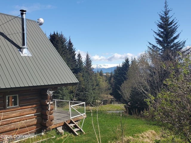 view of grassy yard with a wooded view and a wooden deck