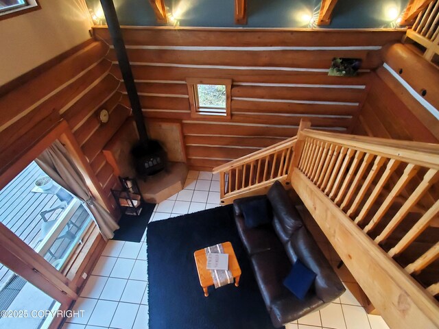 stairway with tile patterned flooring, log walls, and a wood stove