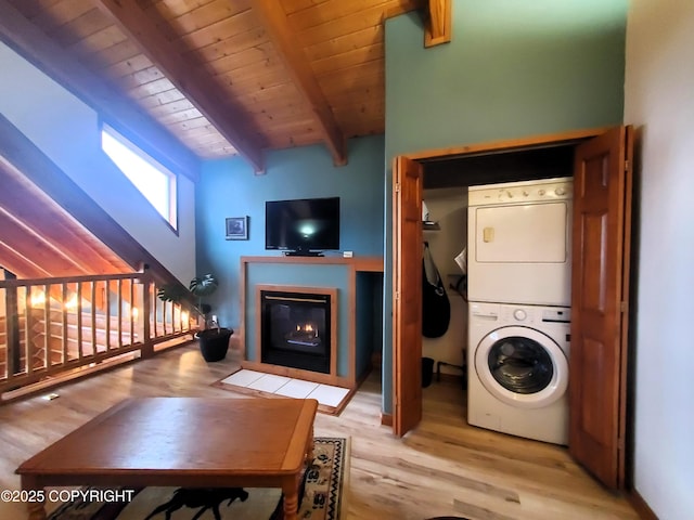 washroom featuring stacked washing machine and dryer, a fireplace with flush hearth, wood ceiling, and light wood-style flooring