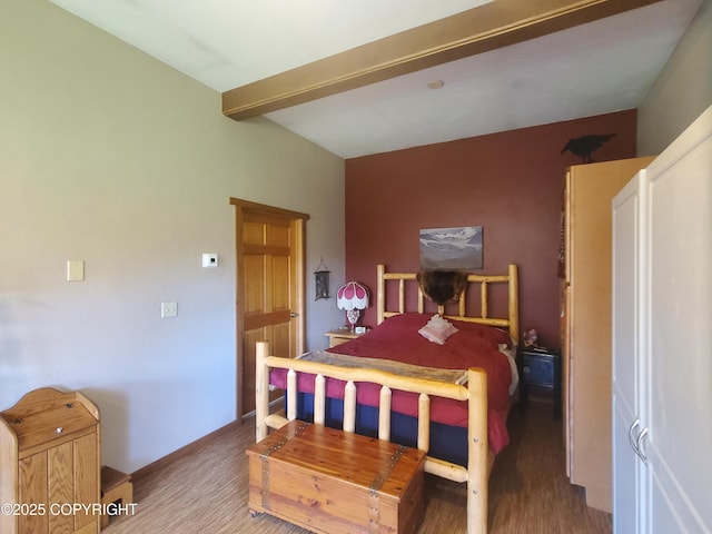 bedroom with wood finished floors and beam ceiling