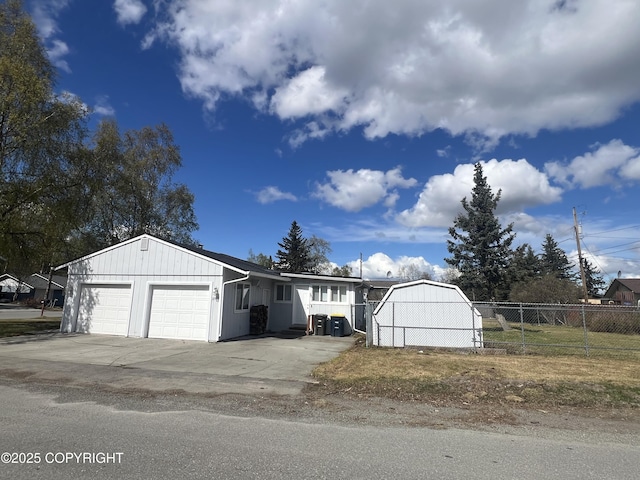 view of outbuilding with fence, an attached garage, and concrete driveway