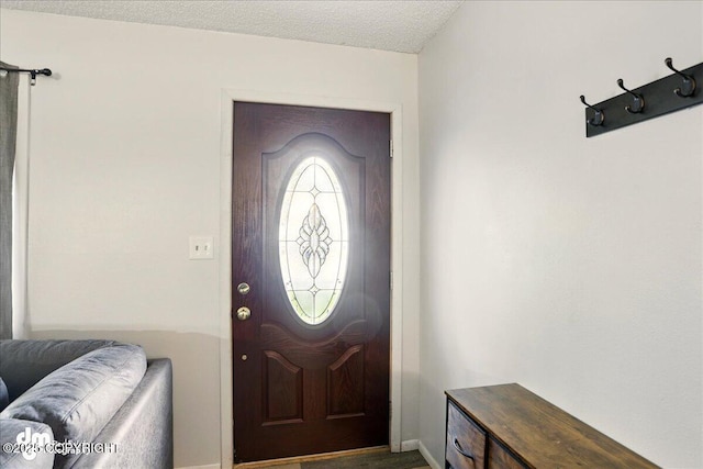 foyer featuring baseboards and a textured ceiling