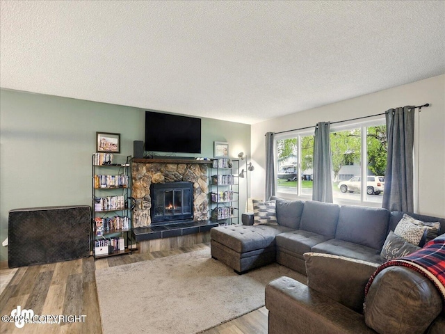 living area featuring wood finished floors, a textured ceiling, and a fireplace