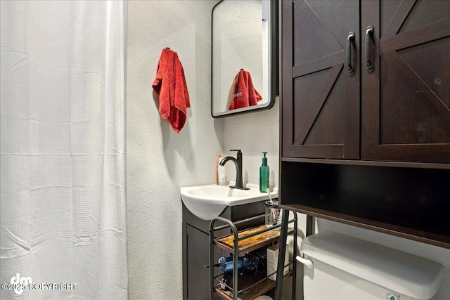 bathroom with vanity, a textured wall, toilet, and a shower with curtain