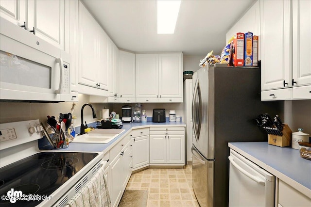 kitchen featuring white appliances, white cabinetry, a sink, and light countertops