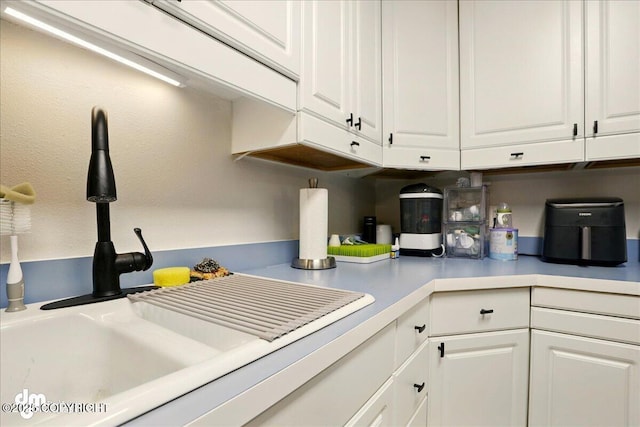 kitchen featuring a sink, white cabinetry, and light countertops
