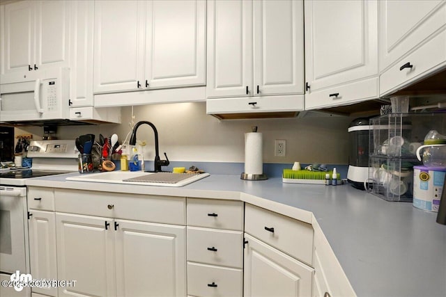 kitchen with white appliances, white cabinetry, light countertops, and a sink