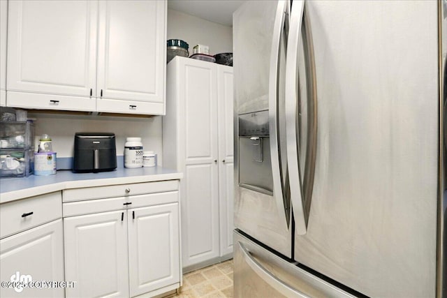 kitchen with stainless steel fridge with ice dispenser, white cabinets, and light countertops