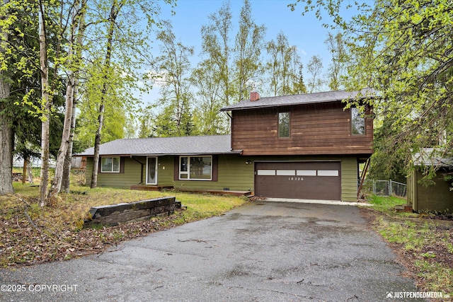 view of front of property featuring a chimney, asphalt driveway, a garage, and fence