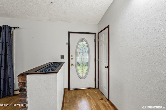 entrance foyer with a textured ceiling, wood finished floors, and a textured wall
