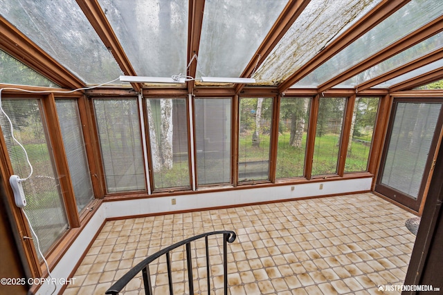 unfurnished sunroom with baseboards and vaulted ceiling