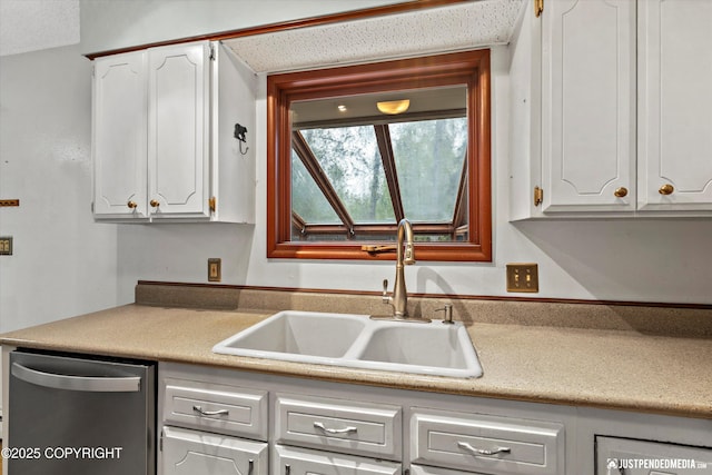 kitchen featuring stainless steel dishwasher, a sink, and white cabinets