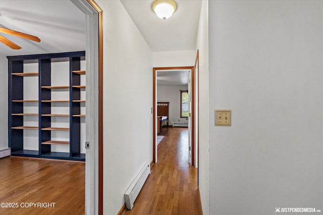 hallway featuring a baseboard heating unit and wood finished floors