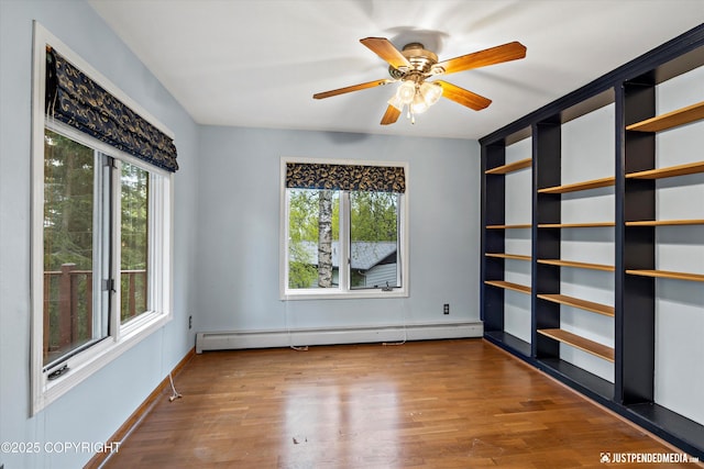 spare room with baseboard heating, wood finished floors, ceiling fan, and baseboards