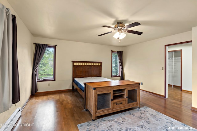 bedroom featuring a baseboard radiator, light wood-type flooring, baseboards, and ceiling fan