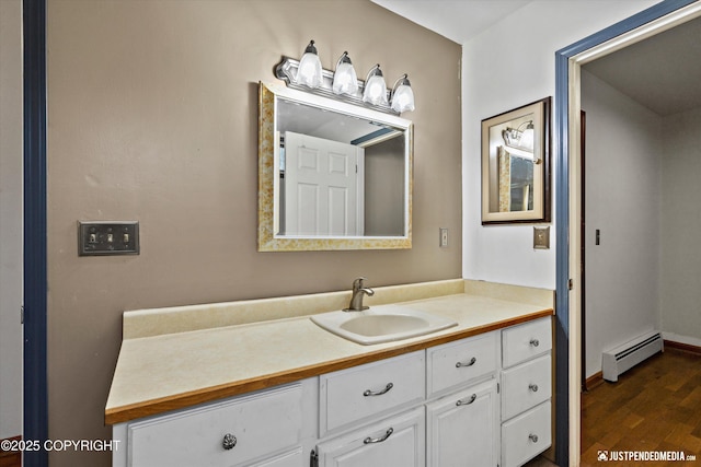 bathroom featuring baseboard heating, wood finished floors, and vanity