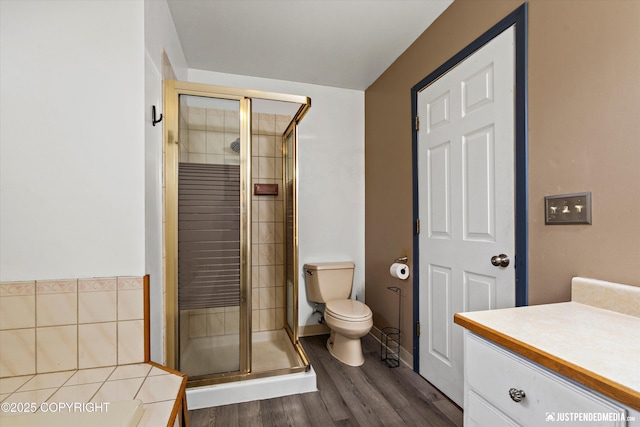 full bath with a shower stall, toilet, wood finished floors, and vanity