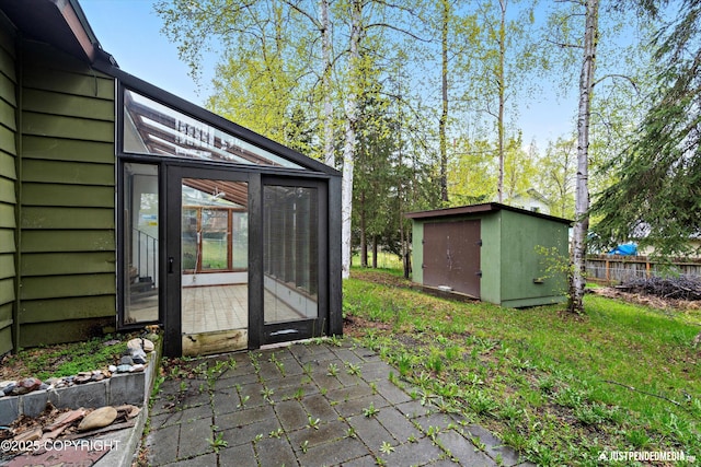 view of patio featuring a shed, an outdoor structure, and a sunroom