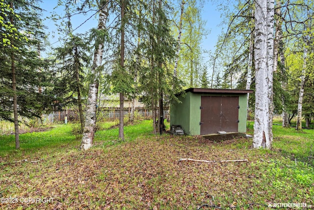 view of yard featuring a storage shed, an outdoor structure, and fence