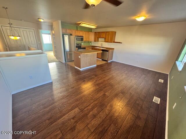 kitchen with stainless steel appliances, open floor plan, a sink, and a center island