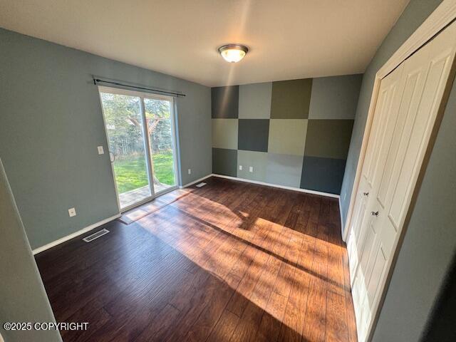 unfurnished room featuring dark wood-style floors and baseboards