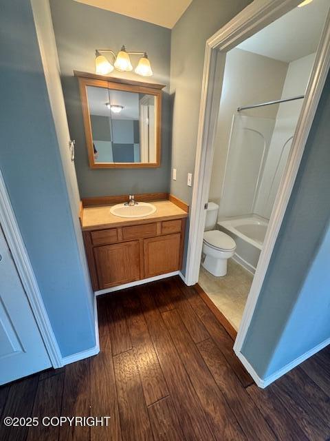 bathroom featuring wood finished floors, toilet, vanity, and bathing tub / shower combination