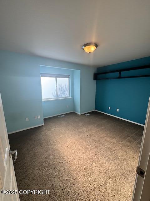 empty room with dark colored carpet and baseboards