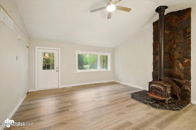 2411 N Friar Tuck Ct, Big Lake, AK 99623 - unfurnished living room with a wood stove, lofted ceiling, a ceiling fan, wood finished floors, and baseboards