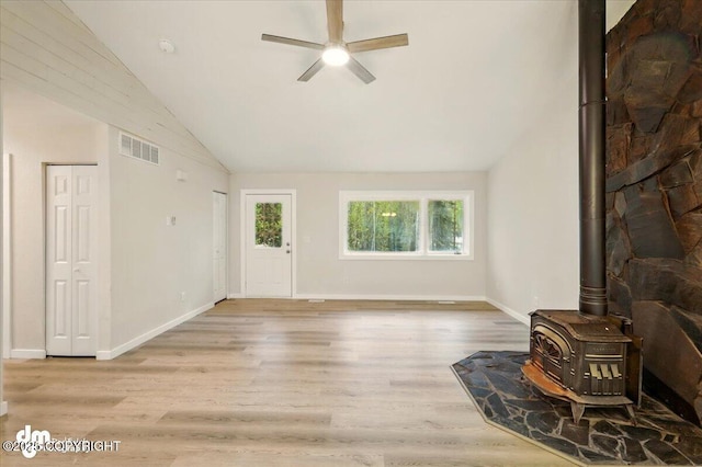 2411 N Friar Tuck Ct, Big Lake, AK 99623 - unfurnished living room with a wood stove, vaulted ceiling, a ceiling fan, wood finished floors, and baseboards