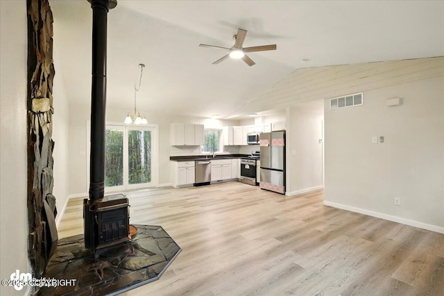 2411 N Friar Tuck Ct, Big Lake, AK 99623 - unfurnished living room featuring a wood stove, a ceiling fan, vaulted ceiling, light wood-style floors, and baseboards