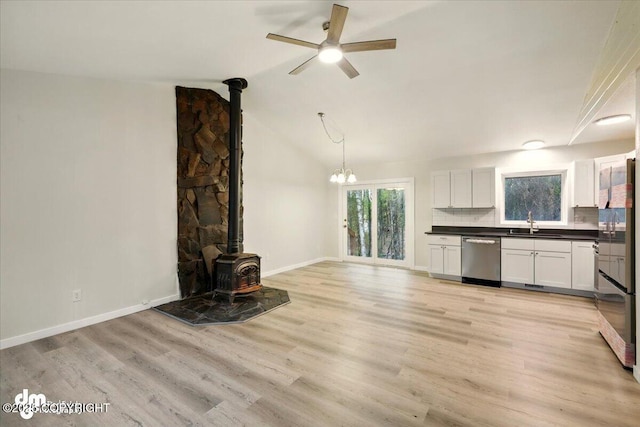 2411 N Friar Tuck Ct, Big Lake, AK 99623 - unfurnished living room featuring a wood stove, a ceiling fan, a sink, light wood finished floors, and baseboards